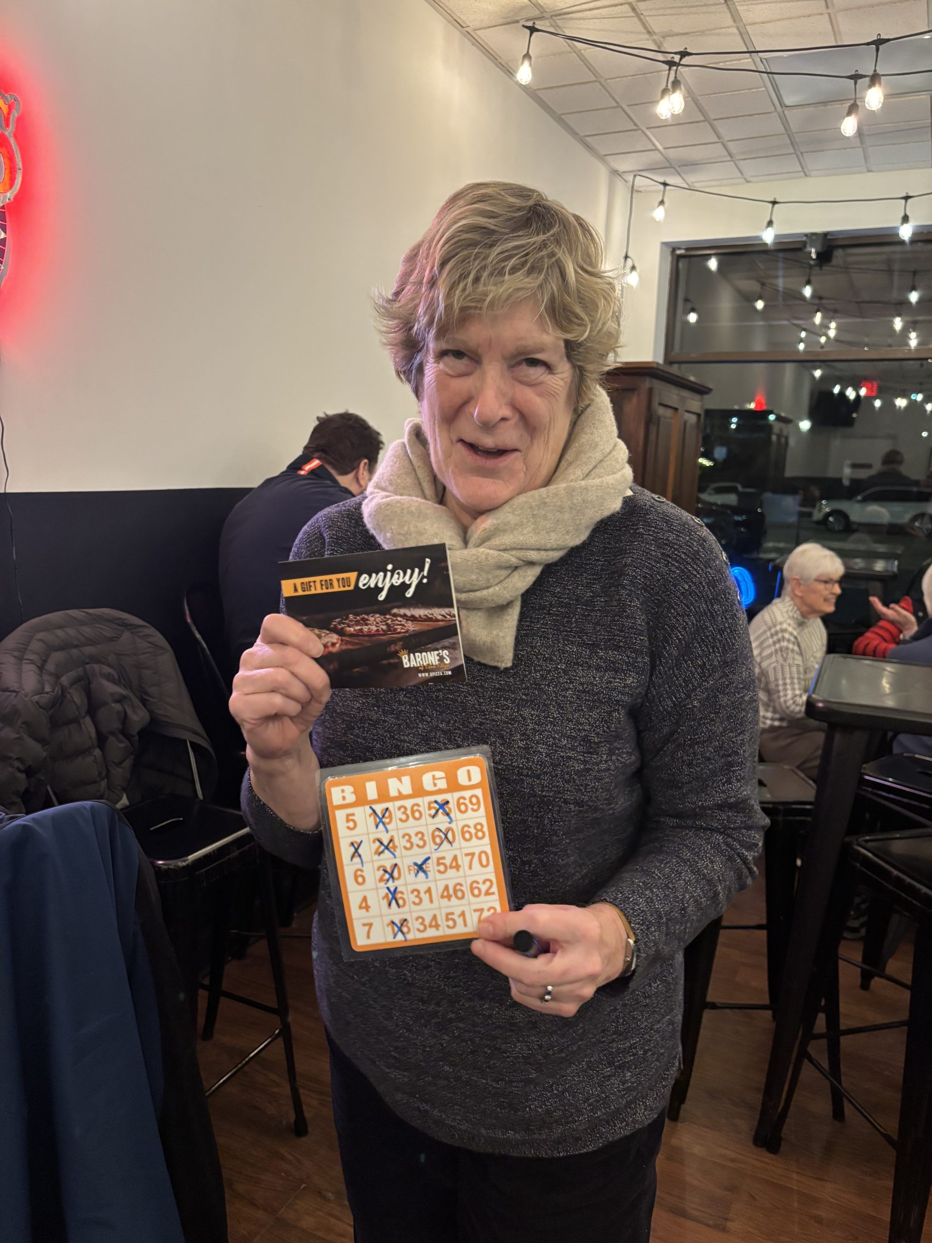 Woman holding gift card with bingo card winner